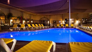 A swimming pool with yellow lounge chairs and a covered area with a patterned ceiling. - Jockey Club Suites (Las Vegas)