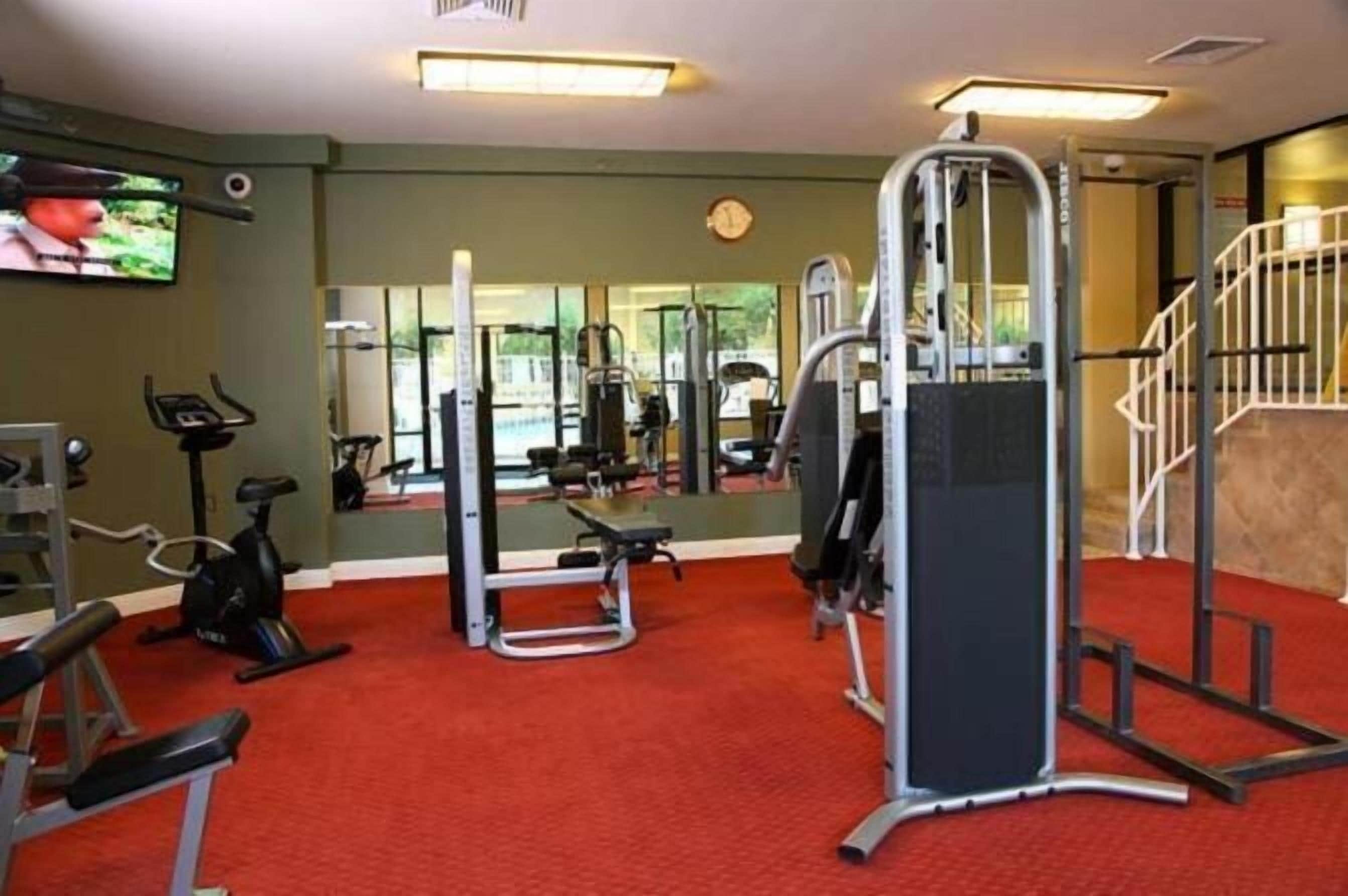 Un gimnasio con equipo de ejercicio, una cinta de correr y un televisor en la pared.