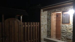 En træport der fører til en indgang med stenvægge og et lille vindue.