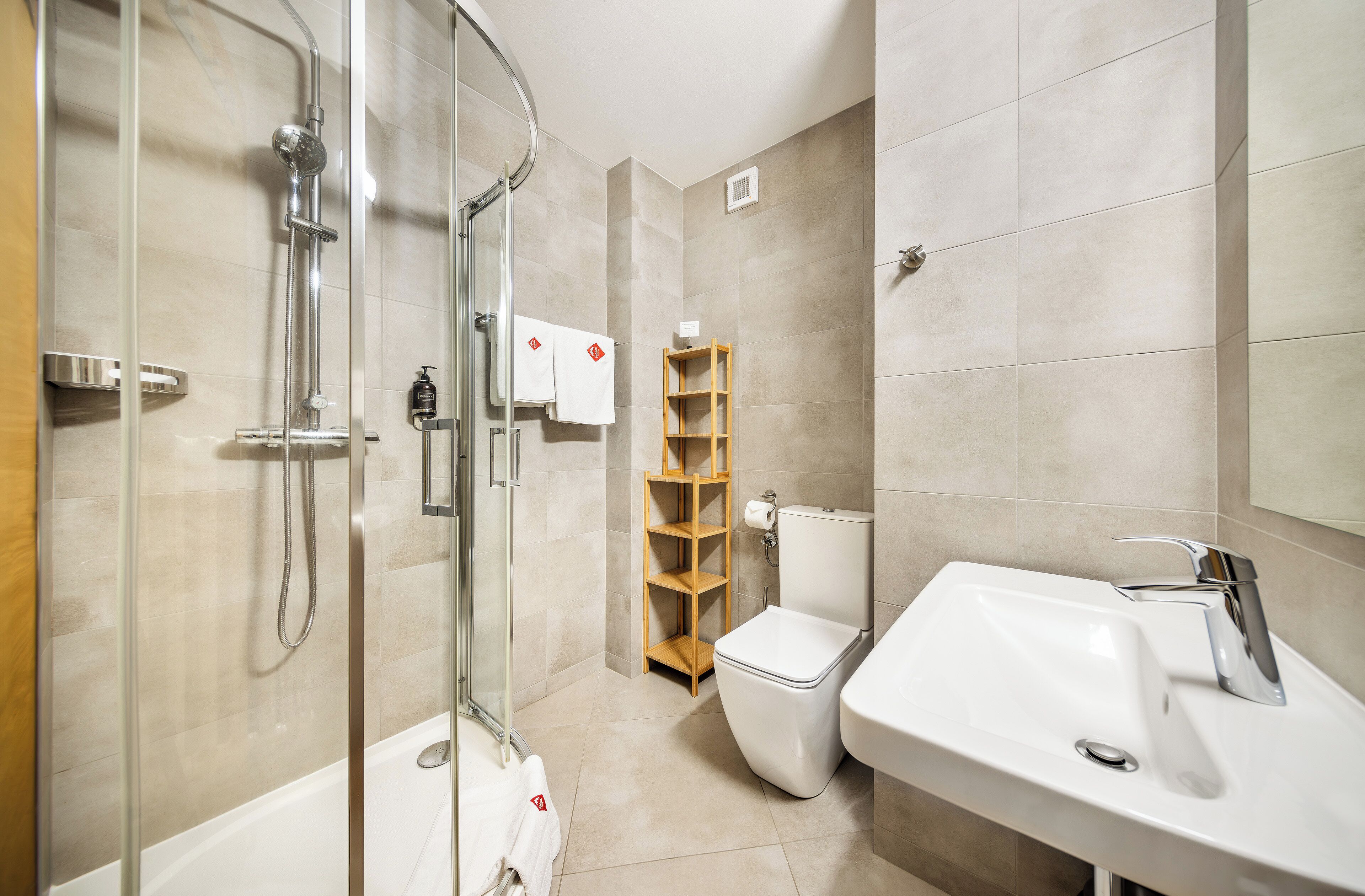 Un baño moderno con ducha de vidrio, un lavamanos blanco y un inodoro.
