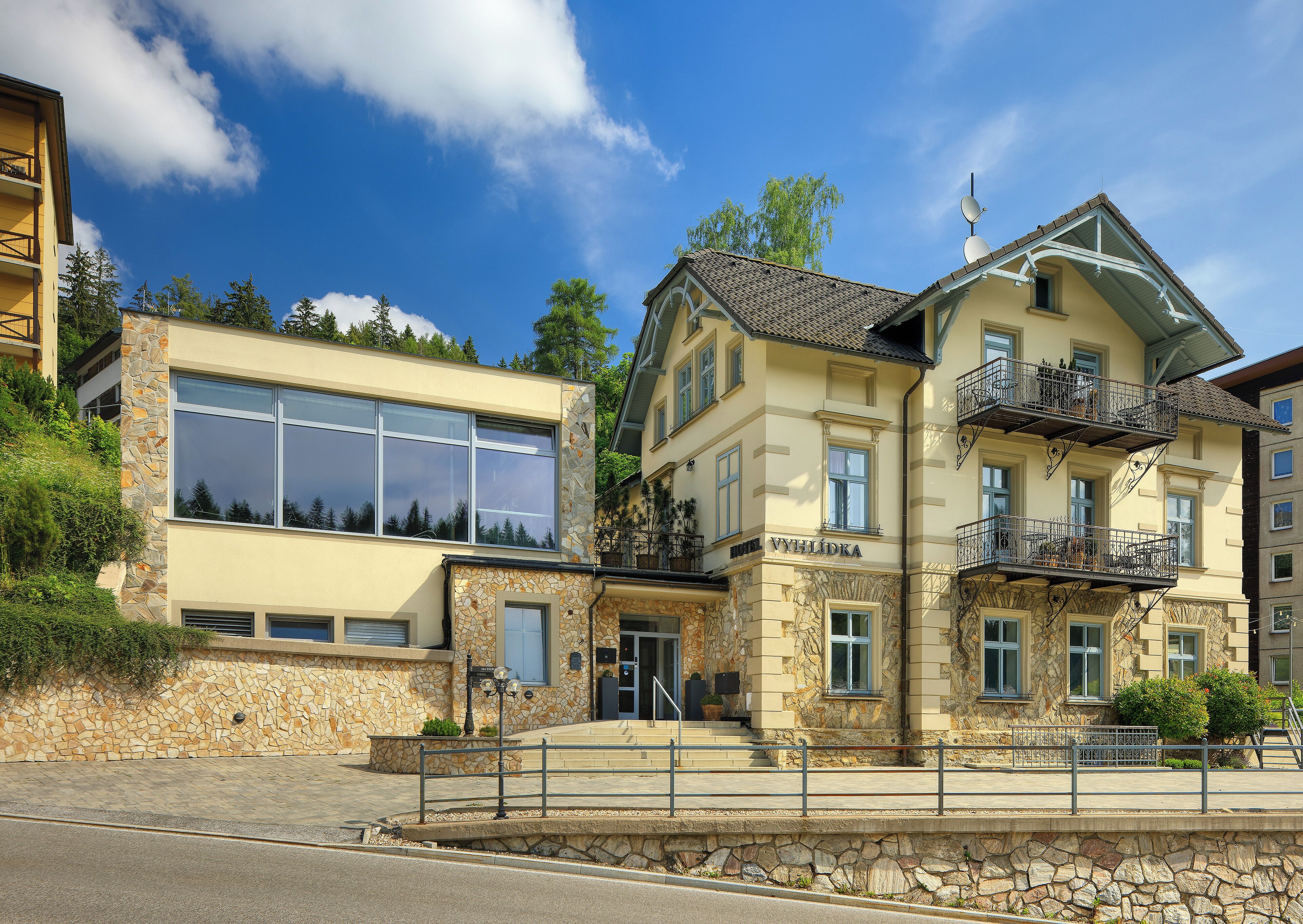 A hotel with a stone facade, large windows, and balconies.