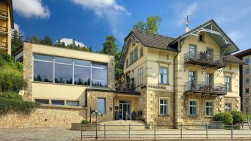 A hotel with a stone facade, large windows, and balconies.