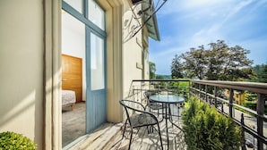 Un balcon avec un plancher en bois, une petite table, deux chaises et une plante en pot.