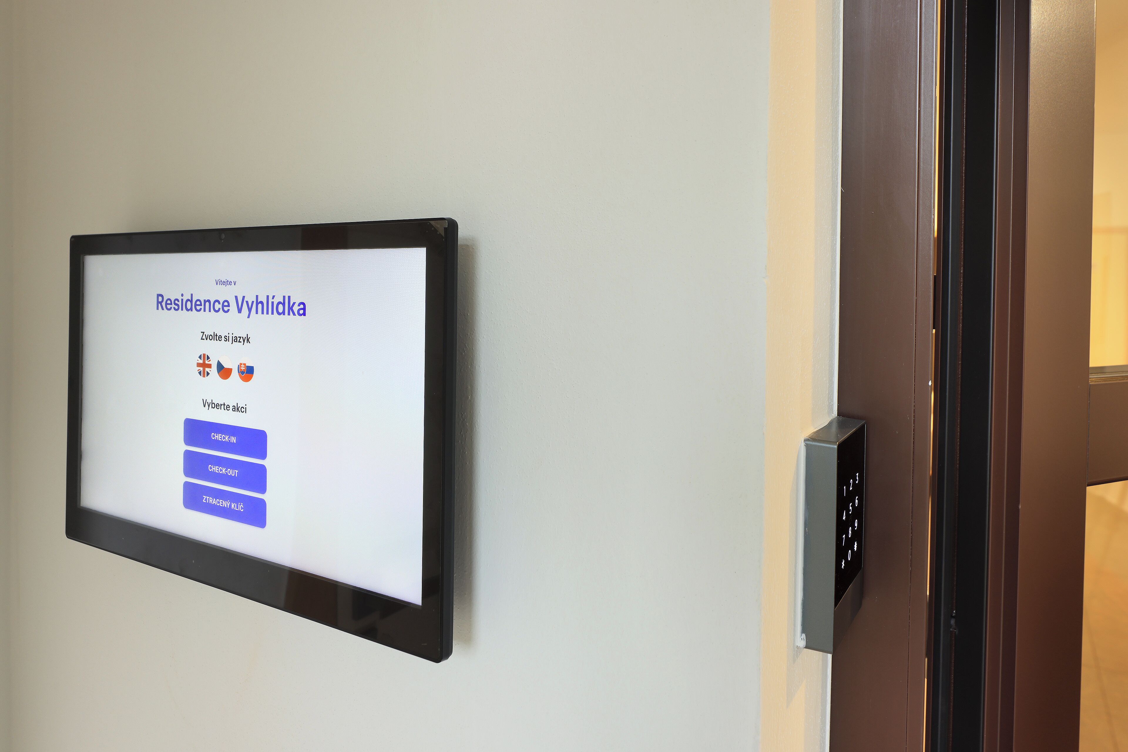 A digital display with a welcome message and options for room check-in.