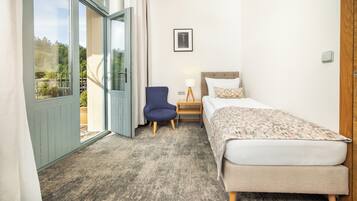 Een slaapkamer met een bed, een stoel, een nachtkastje en een raam.
