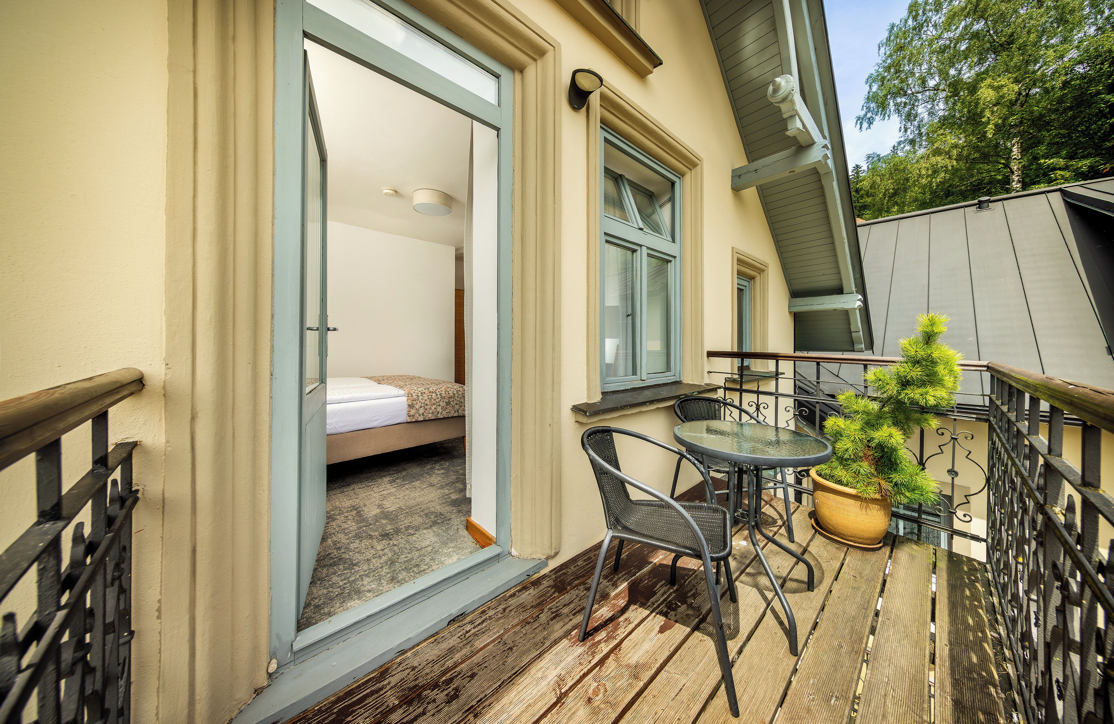 A balcony with a bed, a small table, and a potted plant.