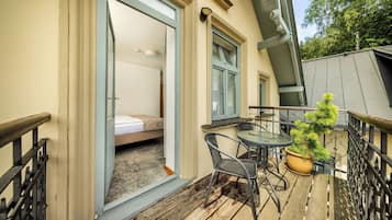 A balcony with a bed, a small table, and a potted plant.