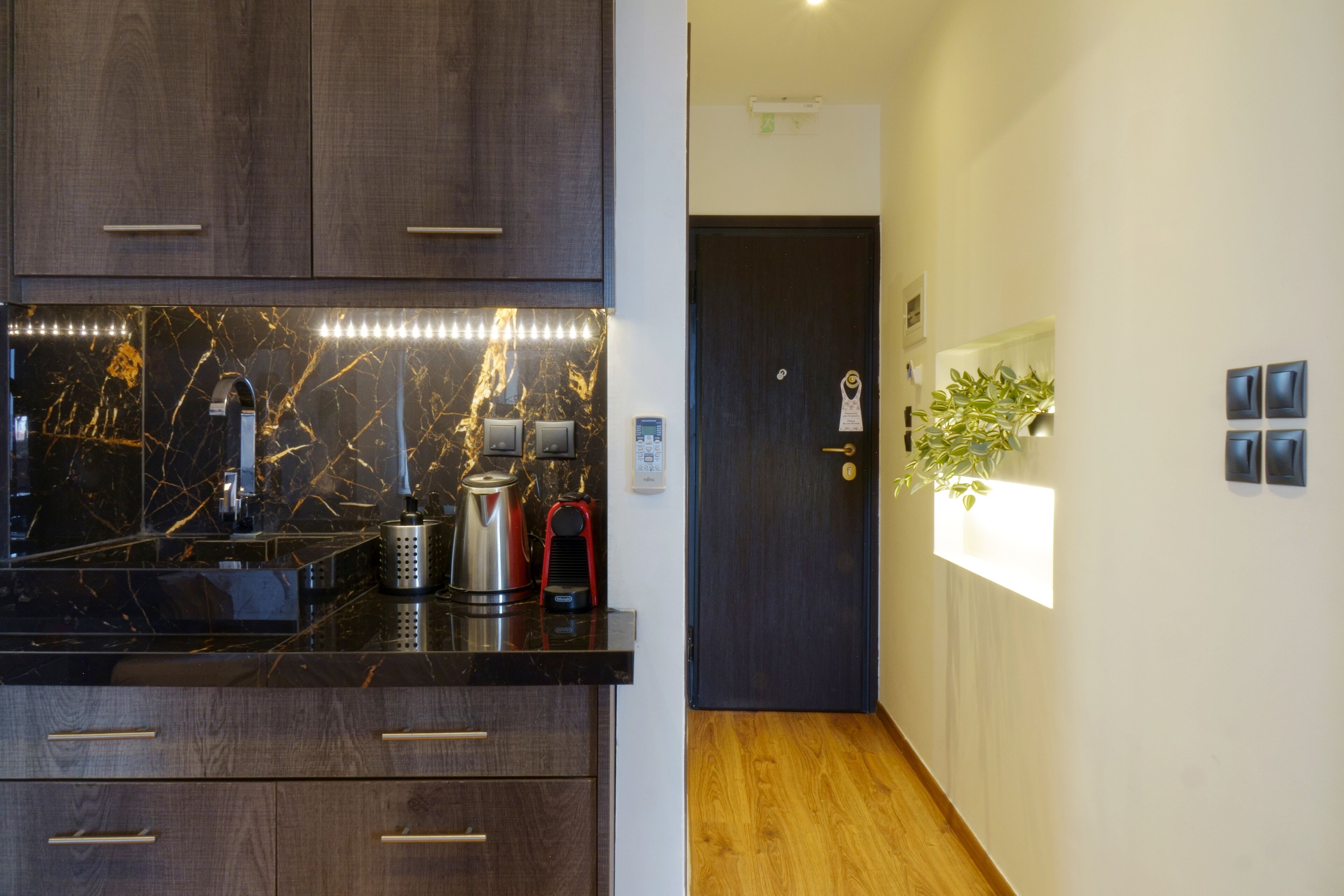 A modern kitchen with dark wood cabinets, a black marble countertop, and a coffee machine.