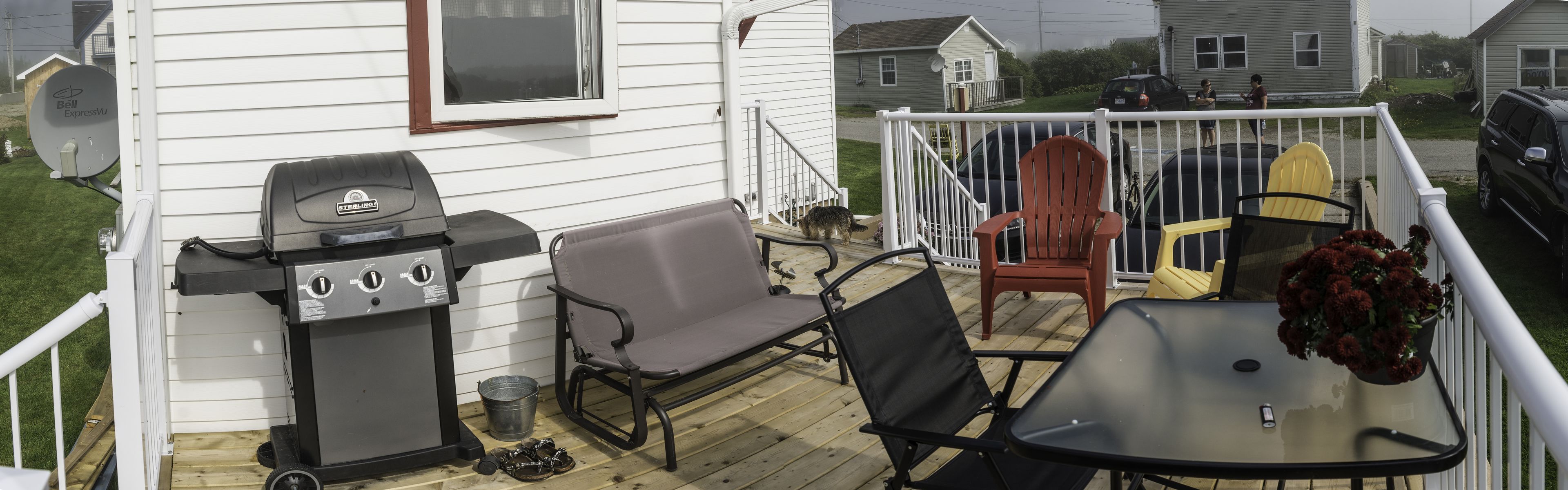 A deck with a grill, chairs, and a table.