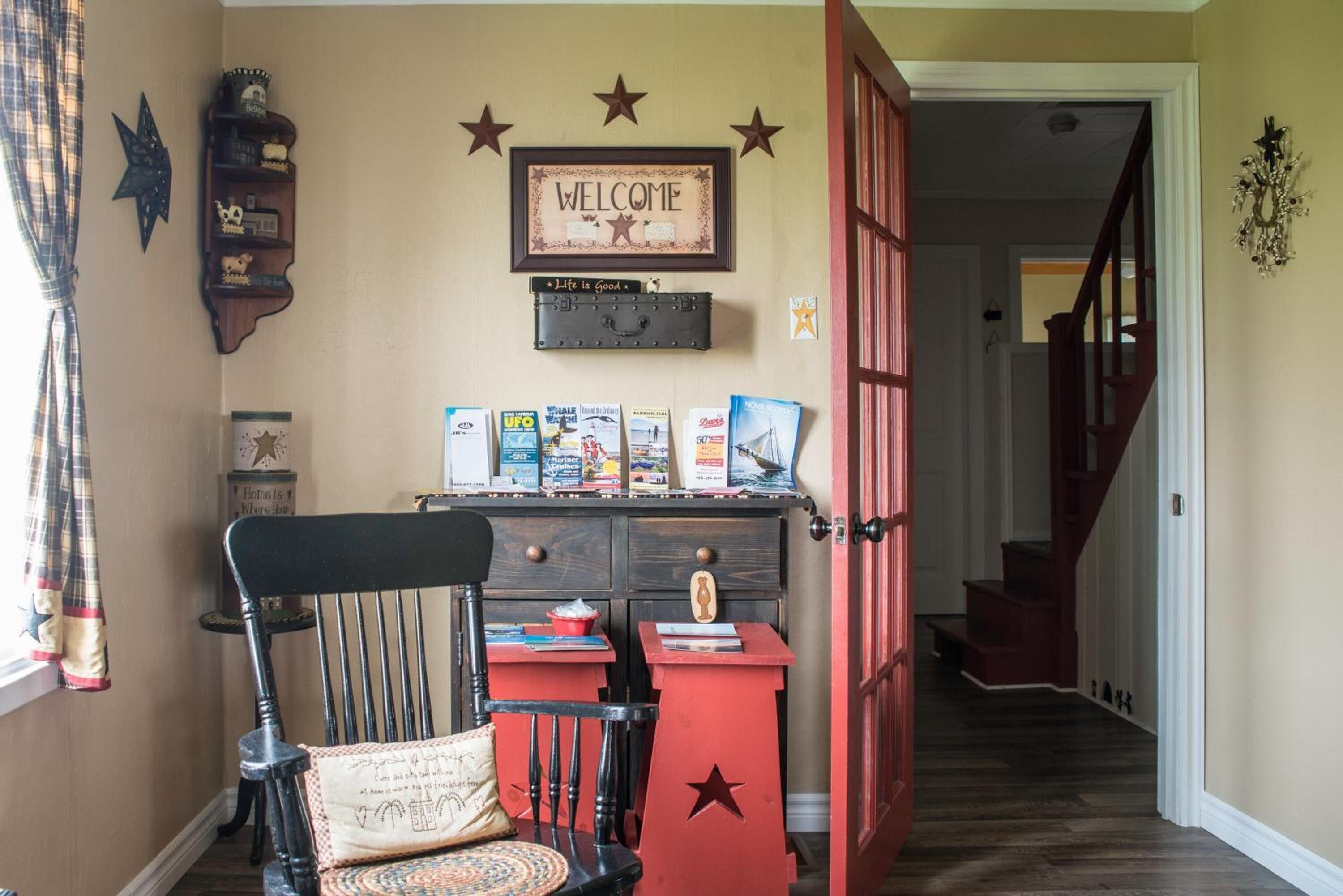 Un recibidor acogedor con una silla de madera, un escritorio rojo y un letrero en la pared que dice 'WELCOME'.