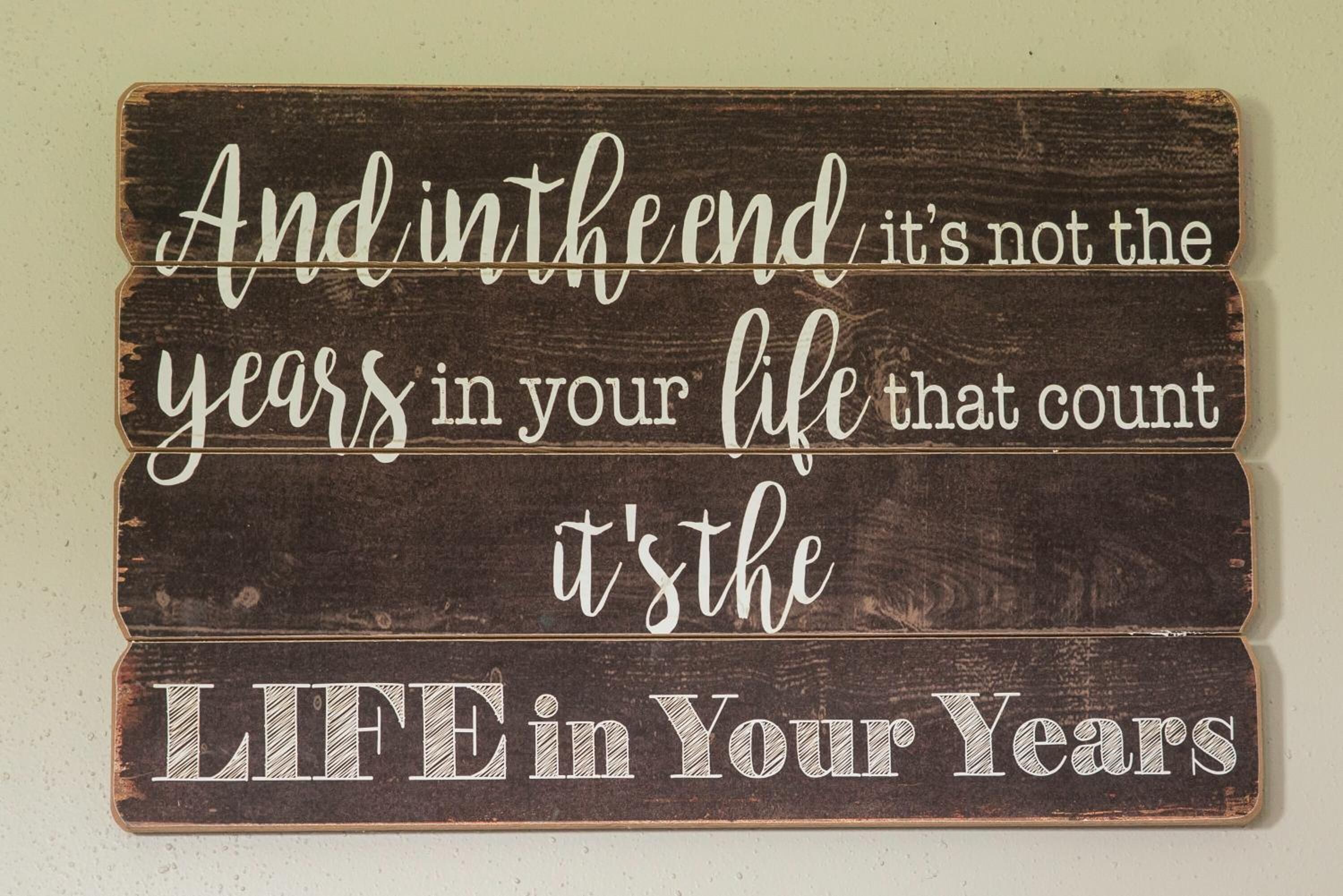 A wooden sign with a motivational quote.