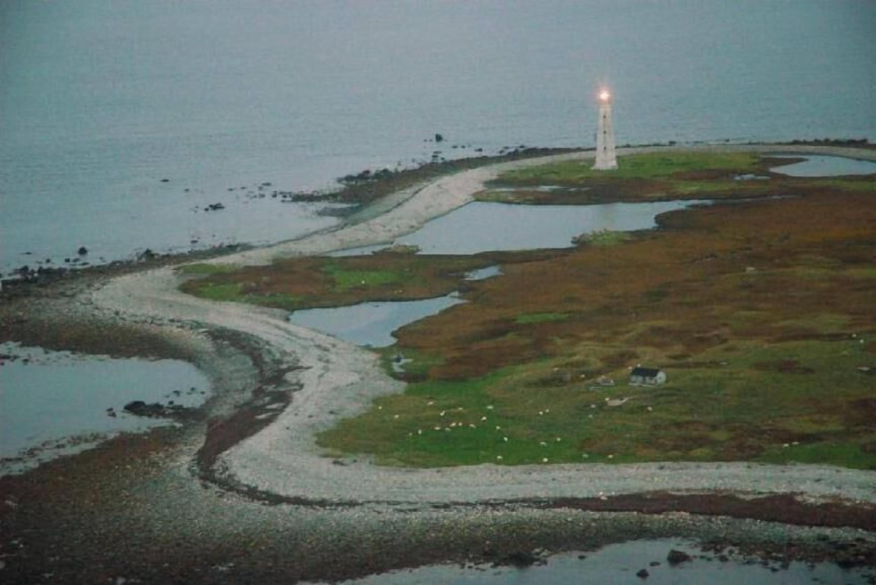 Eine Küstenlandschaft mit einem Leuchtturm, einem gewundenen Pfad und einem kleinen Gebäude.