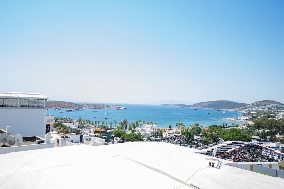 A coastal cityscape with a view of the sea, buildings, and a clear sky.
