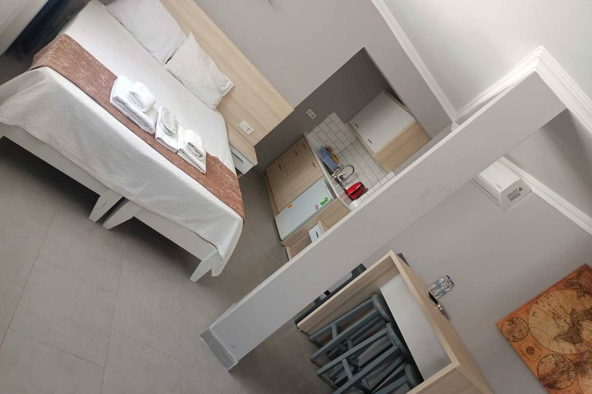A hotel room with a bed, a small kitchenette, and a bathroom.