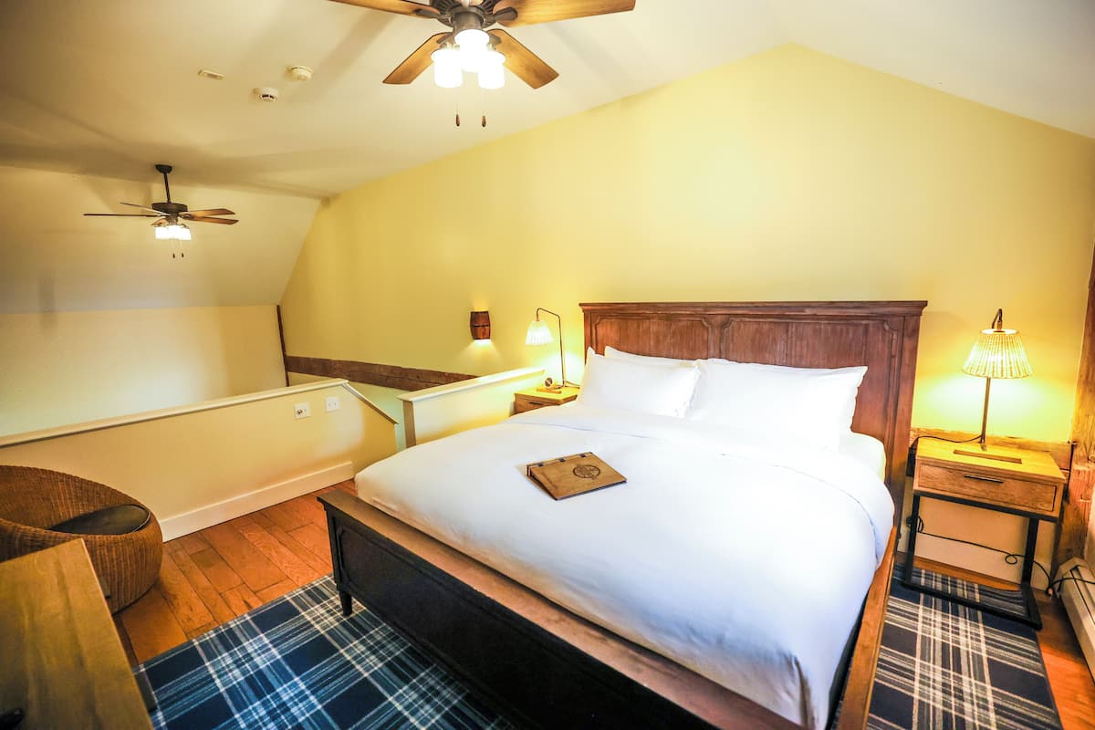 A bedroom with a bed, a ceiling fan, a nightstand, a lamp, and a chair.