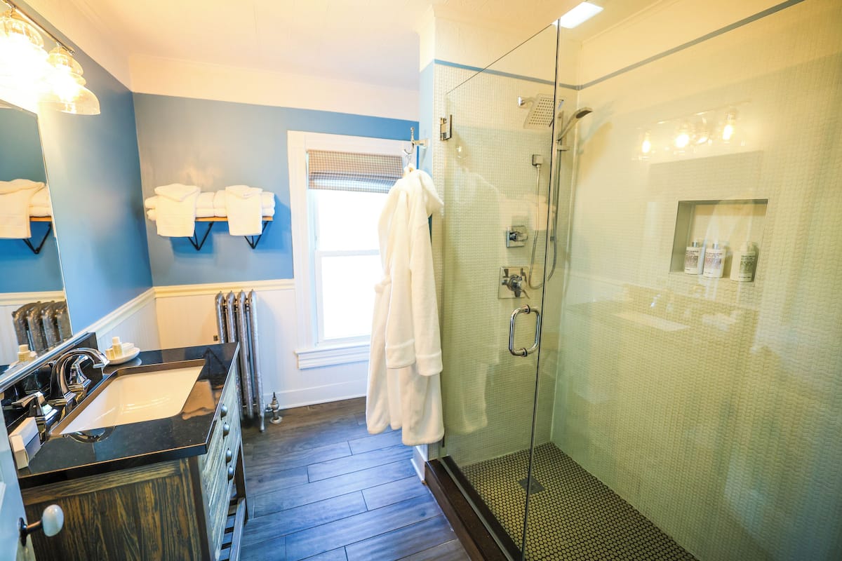 A bathroom with a glass-enclosed shower, a sink with a black countertop, and a mirror with a light fixture.