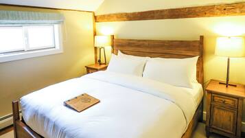 A bedroom with a wooden bed, a ceiling fan, two bedside lamps, and a window with a curtain.