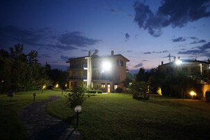 Un edificio de varios pisos con una entrada bien iluminada y un camino que lleva hacia ella.