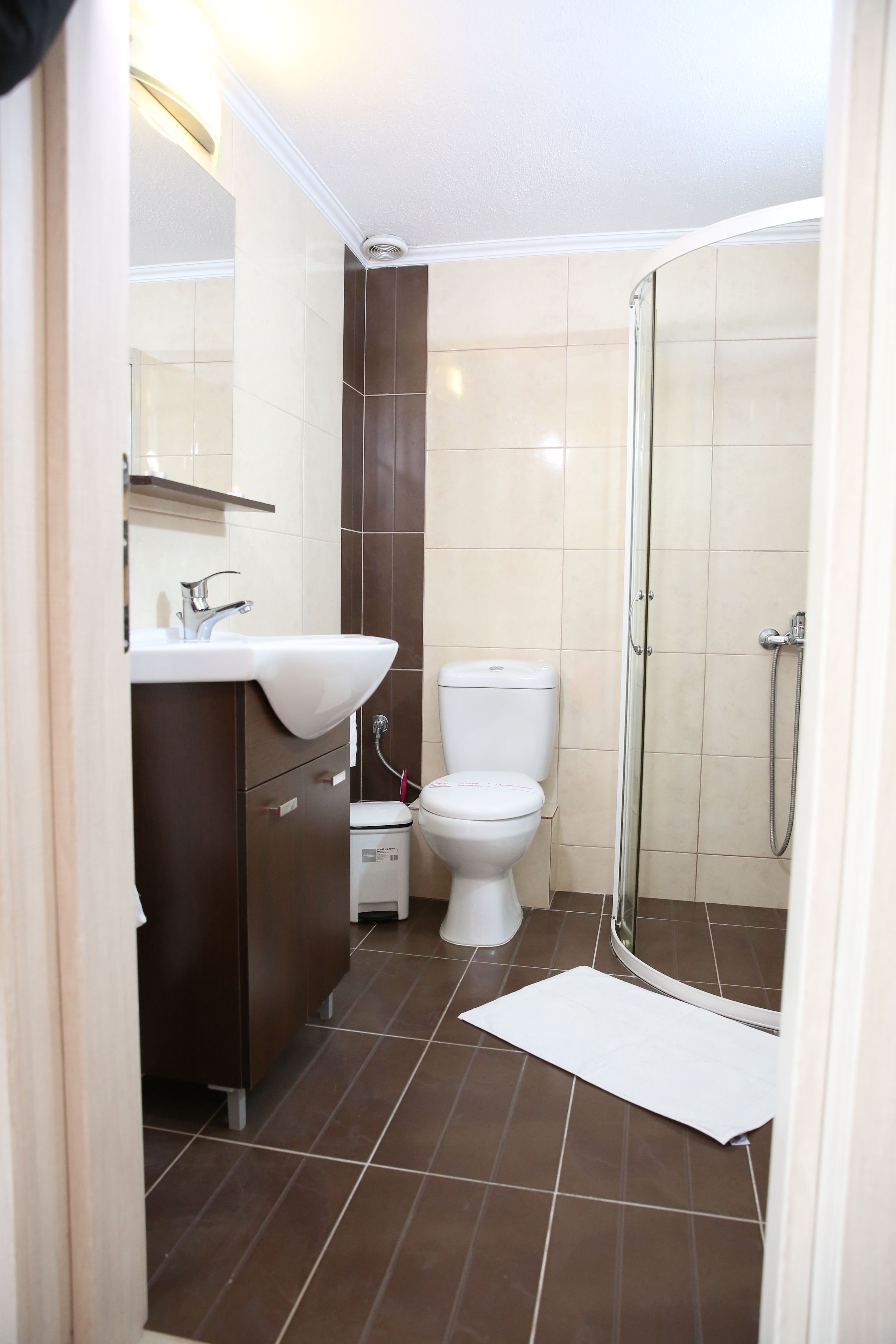 Et badeværelse med vask, toilet og bruser.
