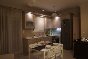 Una cocina moderna con comedor, equipada con electrodomésticos de acero inoxidable, horno empotrado y cafetera.