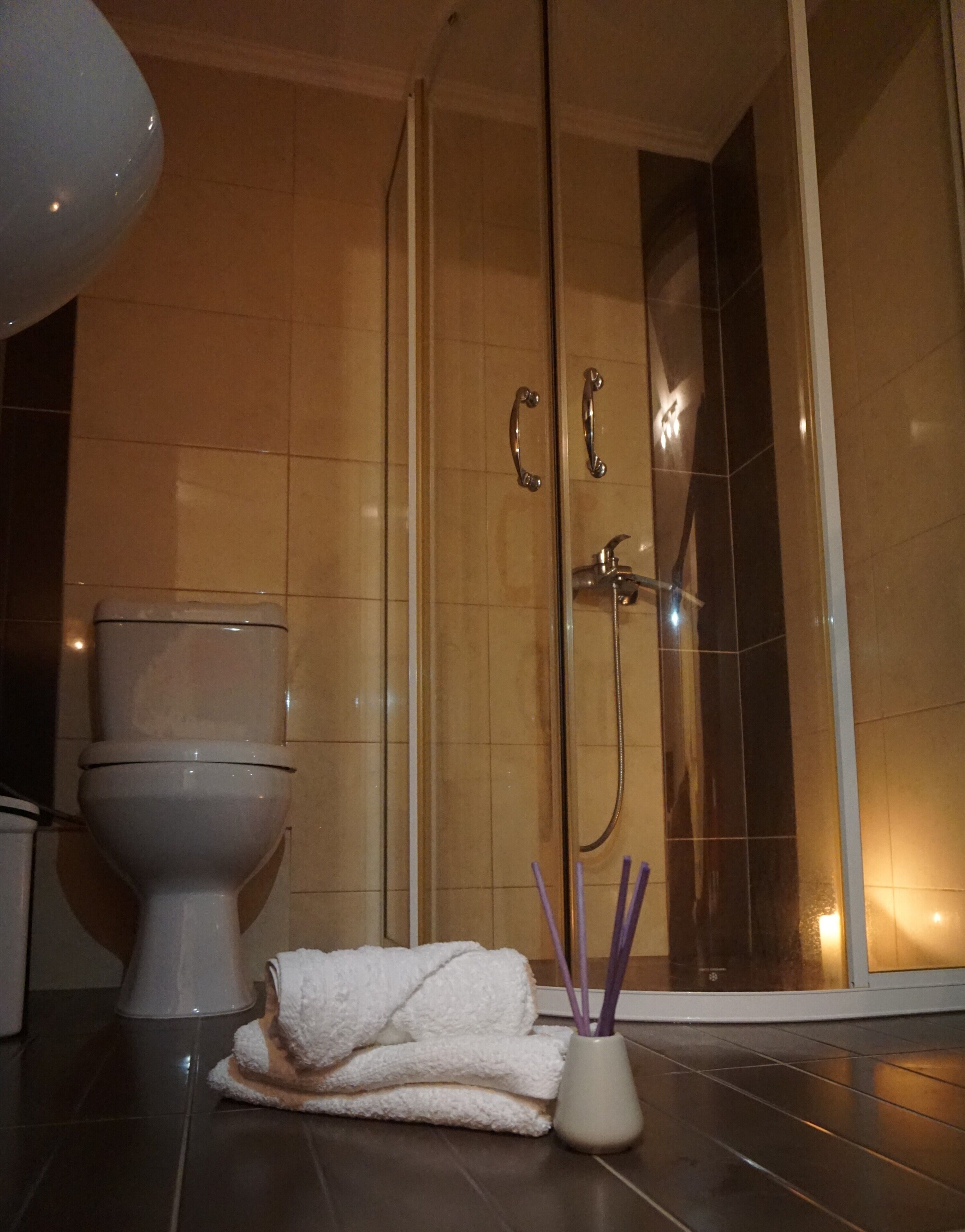 Een badkamer met een toilet, een douche met glazen wanden en een witte handdoek op de vloer.