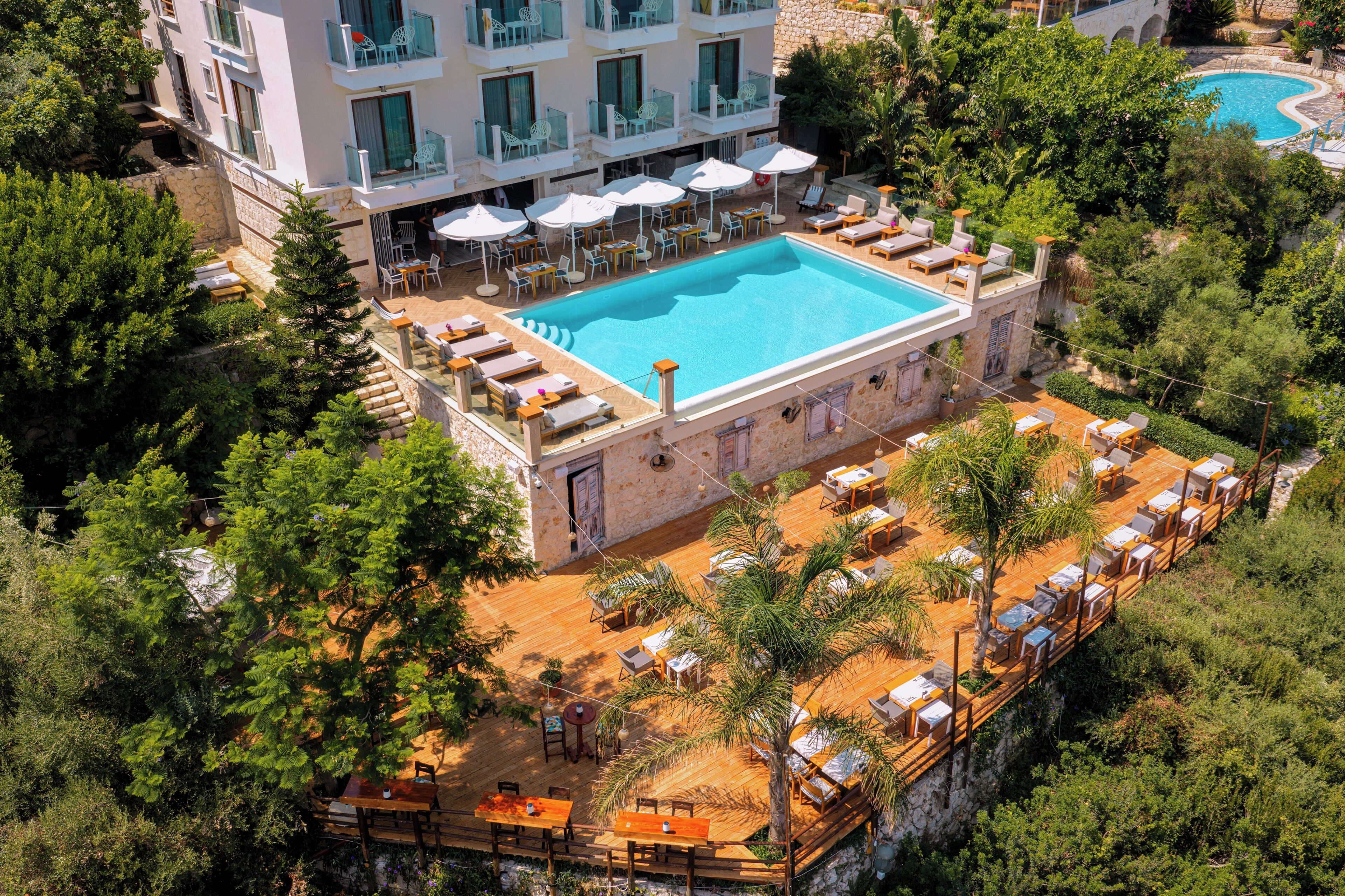A resort with a swimming pool, outdoor seating, and lush greenery.