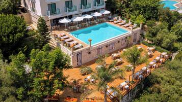 A resort with a swimming pool, outdoor seating, and lush greenery.