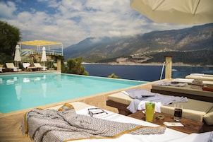 Una piscina al aire libre, sombrillas, sillones reclinables de piscina