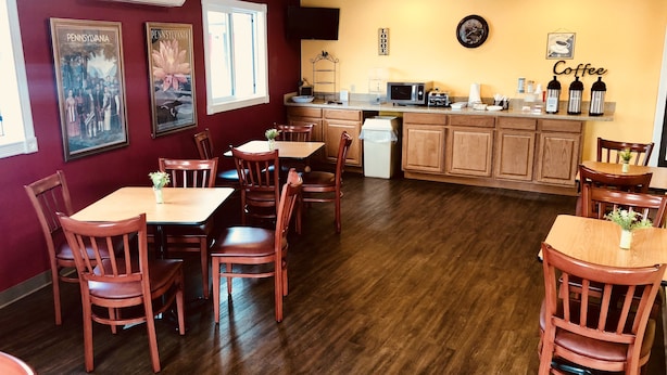A dining area with wooden tables and chairs, a kitchen area with a microwave, and a wall with a 'Coffee' sign. - Hampton Inn (not a Hilton Affiliate) Camp Hill - Harrisburg SW (Camp Hill)