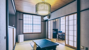 Una habitación japonesa tradicional con suelo de tatami, una mesa baja, puertas correderas shoji y un farol colgante.