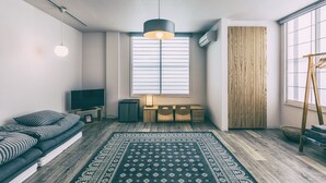 Una sala de estar moderna con un sofá, un televisor, un escritorio de madera, un tapete estampado y un ventanal con persianas.