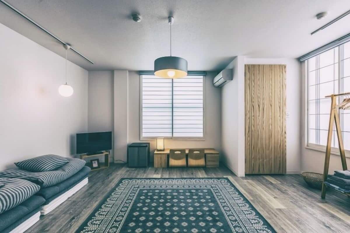 Una sala de estar moderna con un sofá, televisor y un ventanal grande.