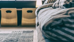 Una cama con un edredón a rayas, una alfombra estampada y dos mesitas de noche de madera.
