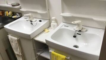 A bathroom with two white sinks, a mirror, and a towel rack.