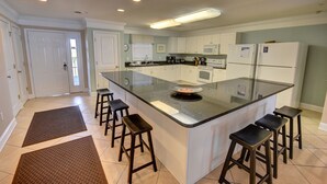 Una cocina moderna con una isla central, armarios blancos y un microondas.