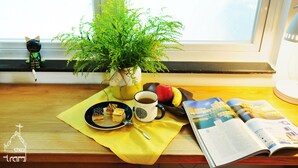 Una mesa con una planta, una taza, un plato de comida y una revista.