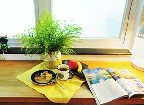 Una taula amb una planta, una tassa, un plat amb menjar i una revista.