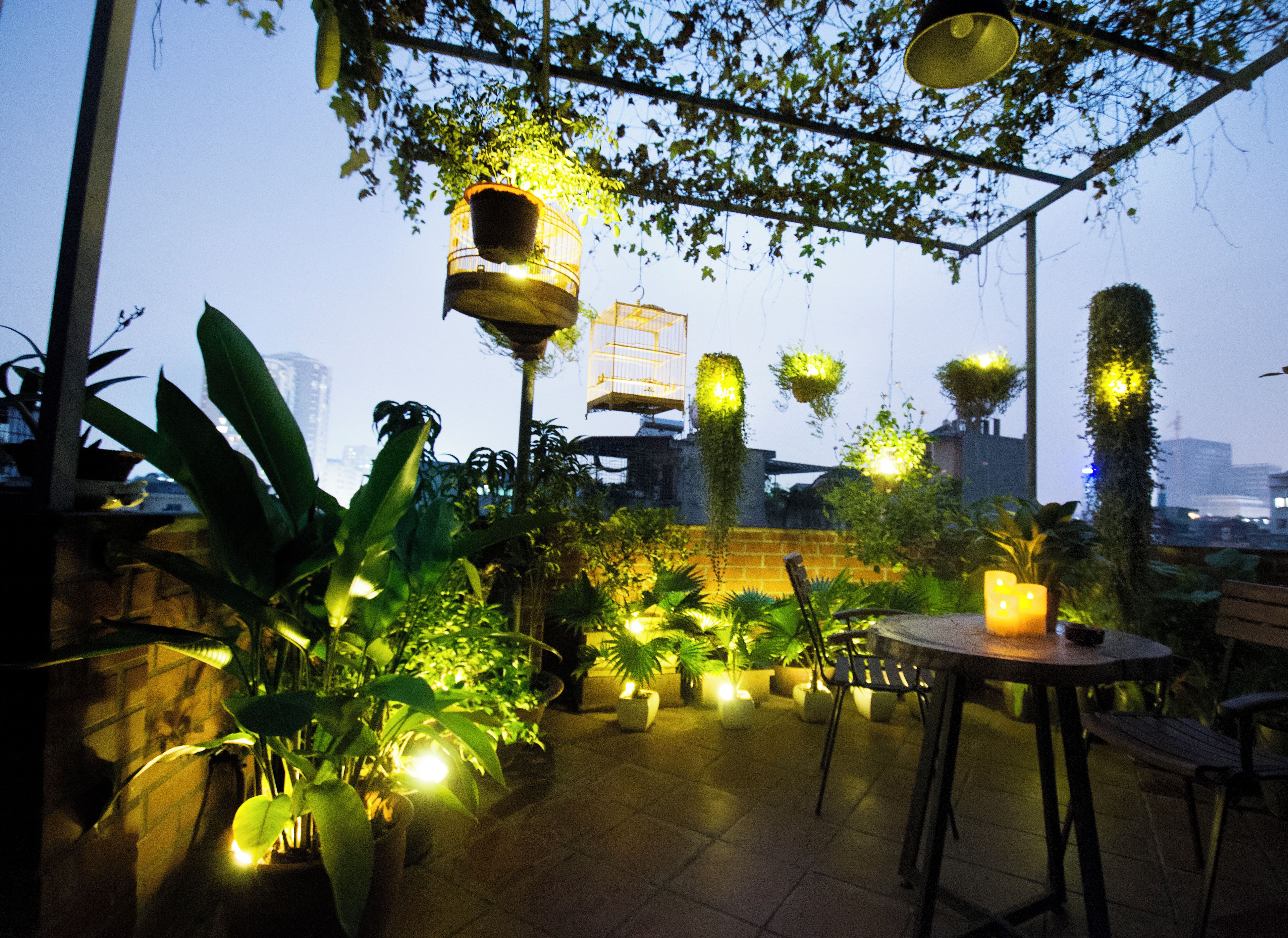 Un espace extérieur aménagé en terrasse, avec des plantes en pot, des jardinières suspendues et une table entourée de chaises.