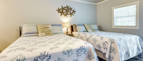 Two beds with matching blue leaf-patterned bedding, a star-shaped wall decoration, and a window with blinds.