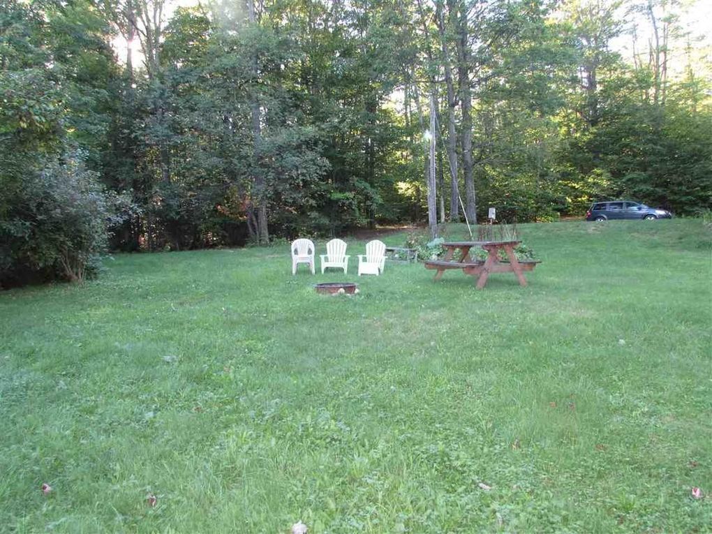 Un espace extérieur verdoyant avec une table de pique-nique et deux chaises blanches.
