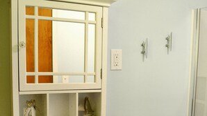 A bathroom with a white sink, a mirror above it, and a cabinet below. There is a blue soap dispenser on the sink.