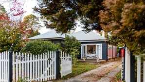 A house with a white picket fence, a stone pathway, and a garden.