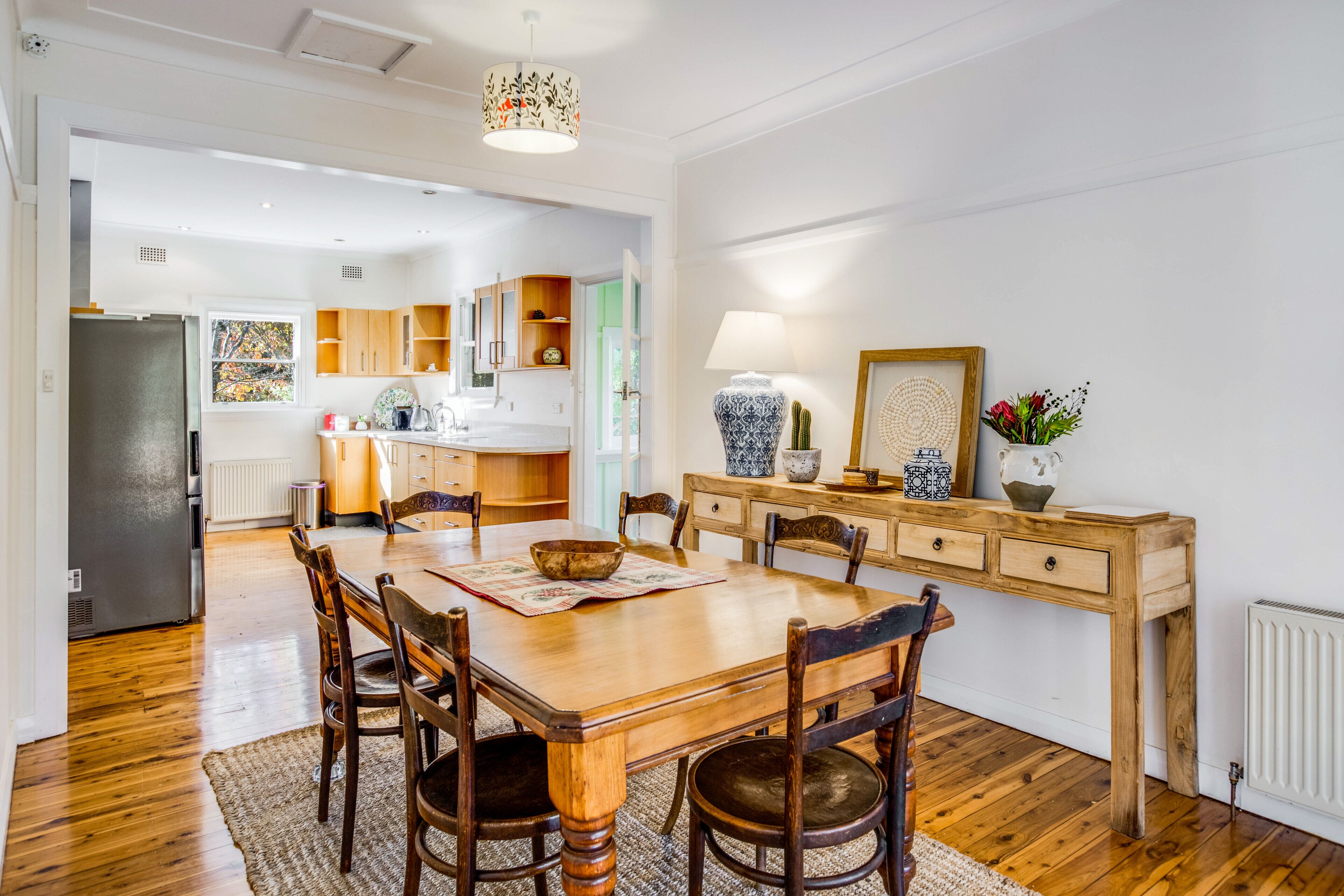 Un'ampia cucina con mobili in legno, un tavolo da pranzo e sedie. C'è un frigorifero, un lavello e una finestra con vista.