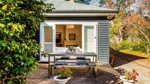 A house with a patio, a table with chairs, and potted plants.