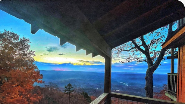 Varanda coberta com vista para uma floresta e paisagem distante.