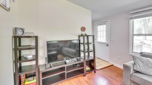 Een woonkamer met een tv-meubel met glazen blad, een boekenkast en een grijze bank.