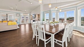 Une cuisine spacieuse avec un coin repas, des chaises blanches et une grande table en bois.