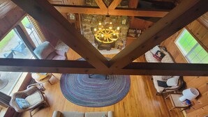 Een houten interieur met hoge plafonds, een centrale kroonluchter, een rond tapijt en zithoekjes.