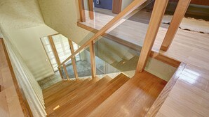 Un escalier en bois avec des rampes en verre menant à l’étage supérieur.