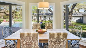 A dining area with a large table, patterned chairs, and a hanging light fixture. - Above Auth Westlake I Pool I Hot Tub I Game Room I Back House I Greenbelt (West Lake Hills)